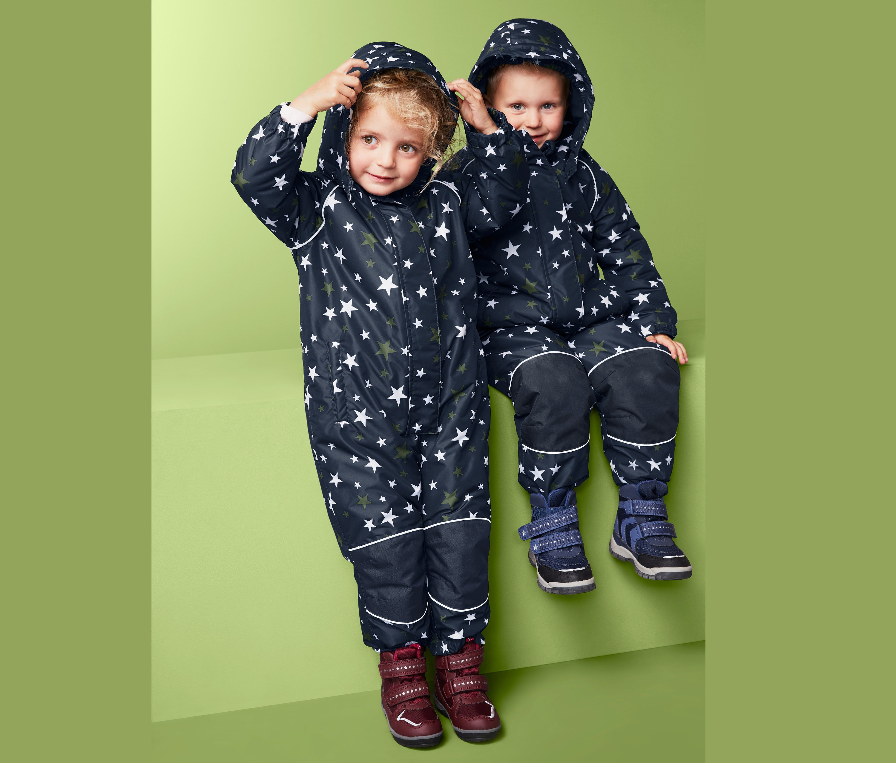 Deti v zimných kombinézach s hviezdami sedia vedľa seba.