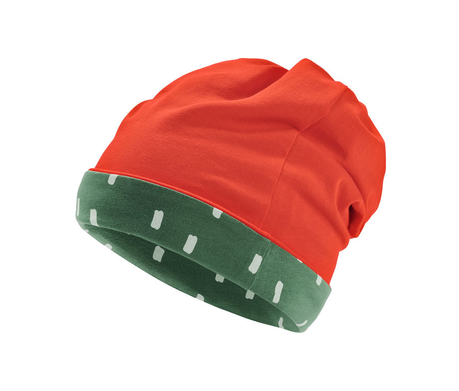 Detail obojstrannej čiapky, oranžovej na vonkajšej strane a zelenej s bielymi bodkami na vnútornej strane.