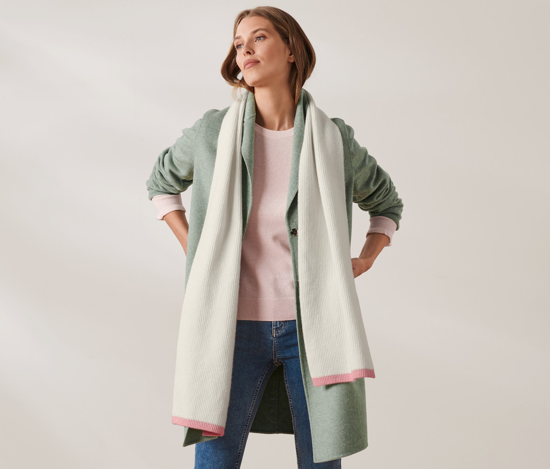 Žena pózuje s rukami vbok a má na sebe pletený šál s vlnou.