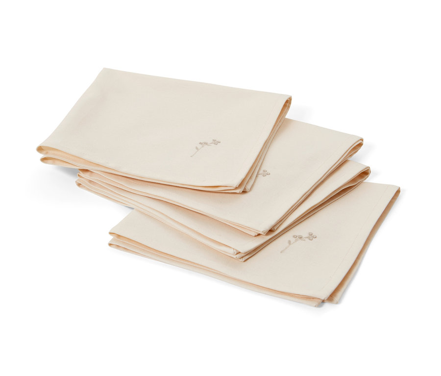 Štyri krémové vyšívané obrúsky ležia zložené na sebe.