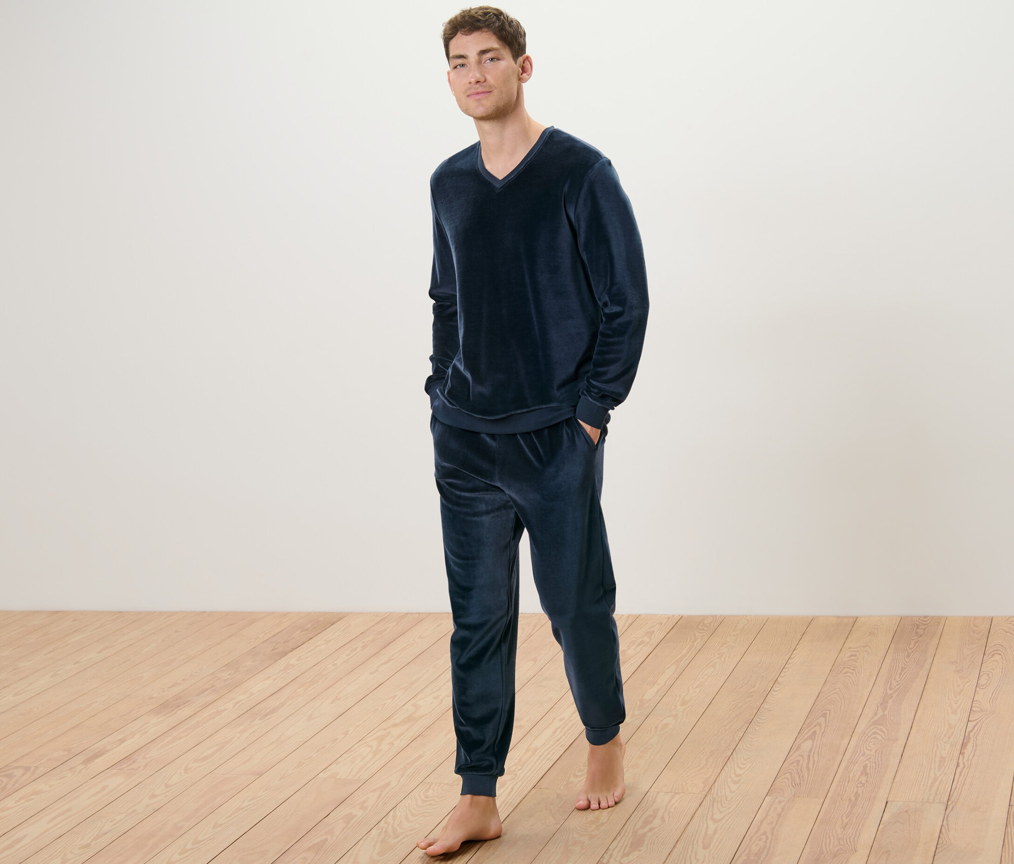 Muž stojí a má na sebe pyžamo z plyšového úpletu.