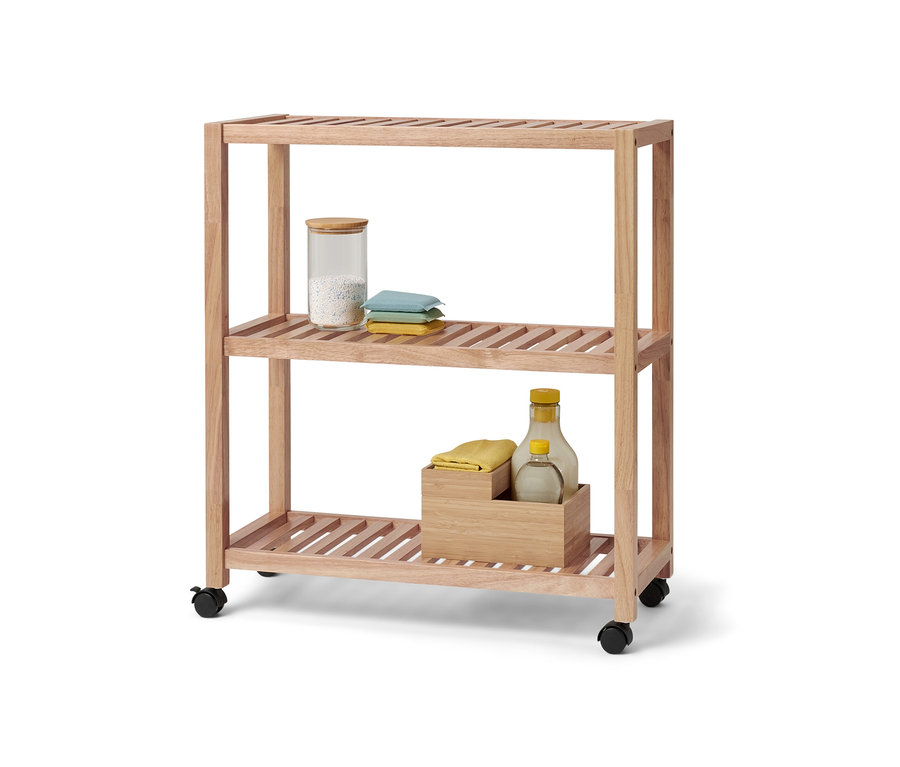 Trojposchodový regál z masívneho dreva s kolieskami. Na hornom poschodí sa nachádza sklenená nádoba a textílie.