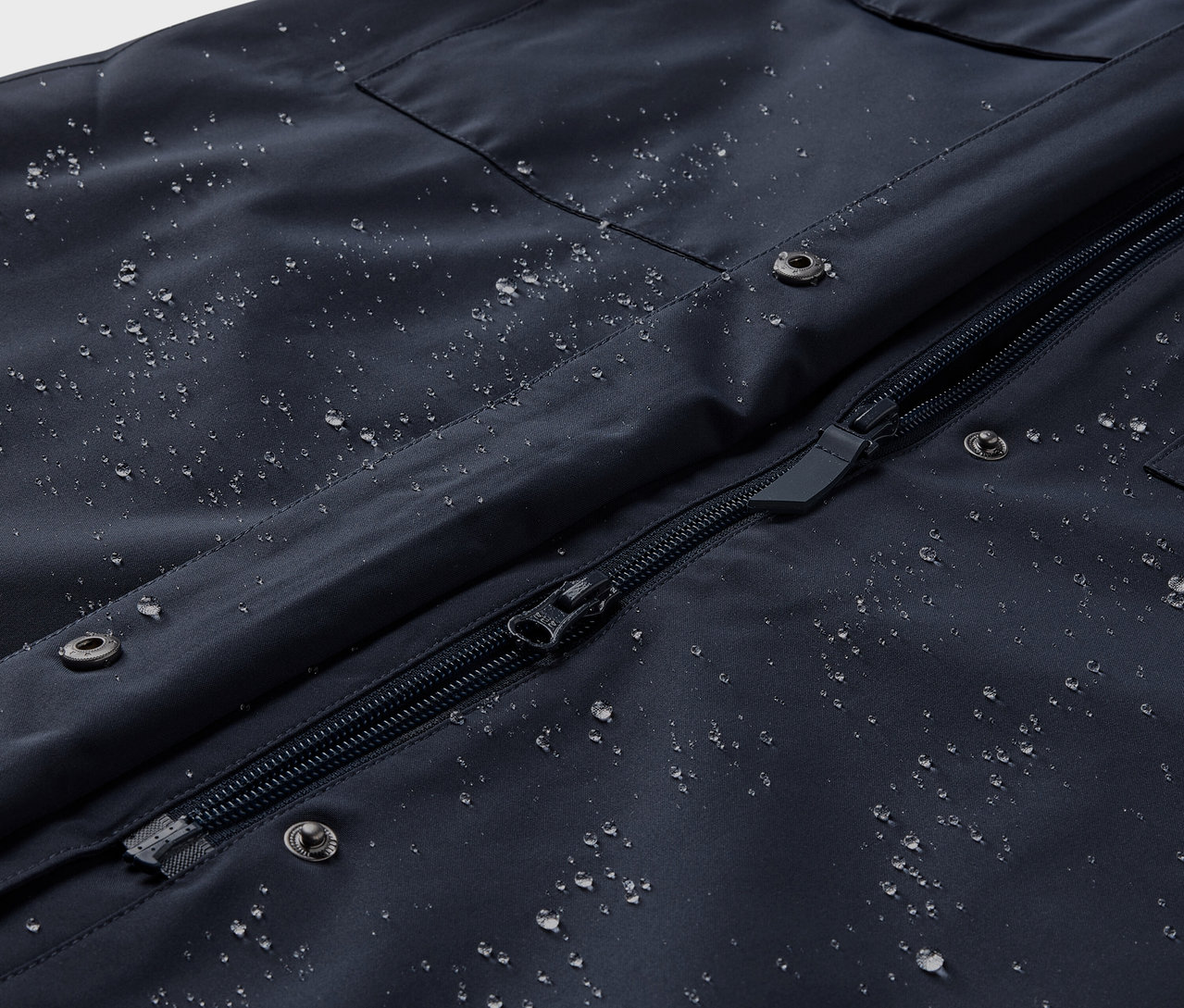 Detailný pohľad na nepremokavý trenčkot s kvapkami vody.