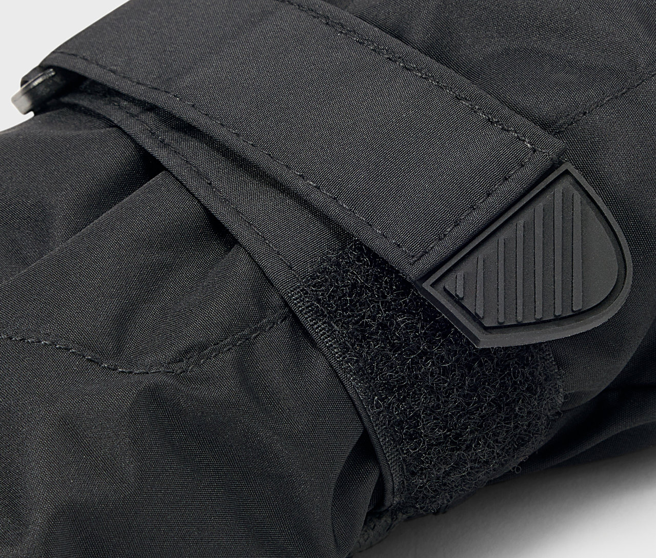 Detail čiernej rukavice so zapínaním na suchý zips a gumovým zakončením remienka.