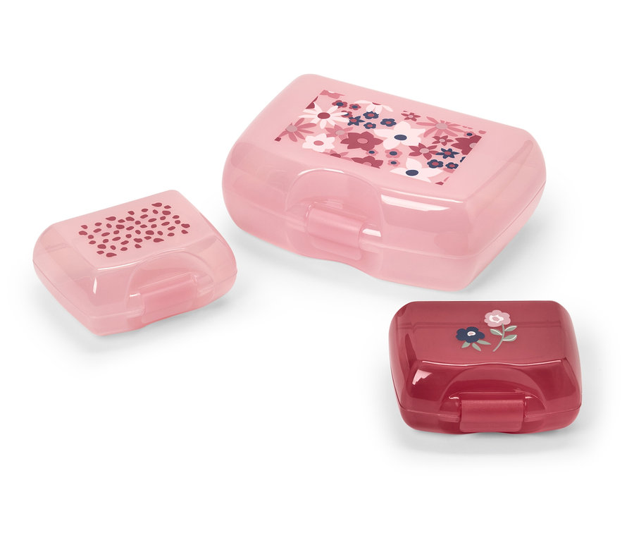 Tri plastové dózy na desiatu rôznych veľkostí a farieb s kvetinovými vzormi.