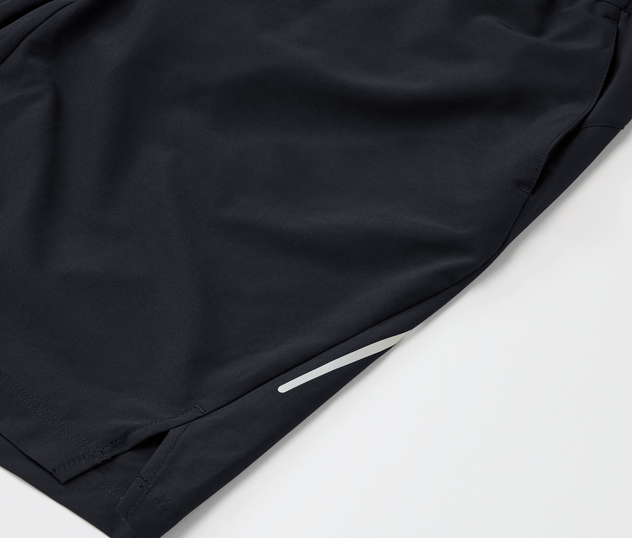 Detail čiernych športových šortiek s vreckom a reflexným prúžkom.