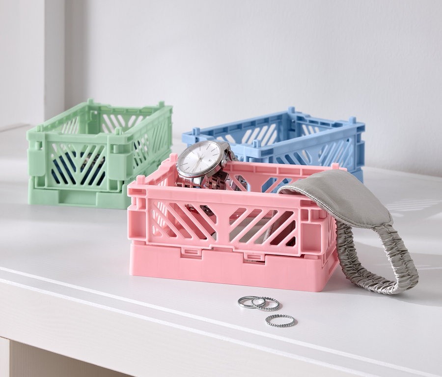 Tri farebné skladacie škatule na stole, jedna ružová s hodinkami, jedna modrá a jedna zelená.