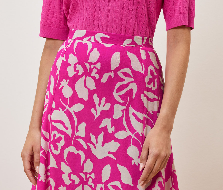 Žena má na sebe ružový top a sukňu s kvetinovým vzorom.