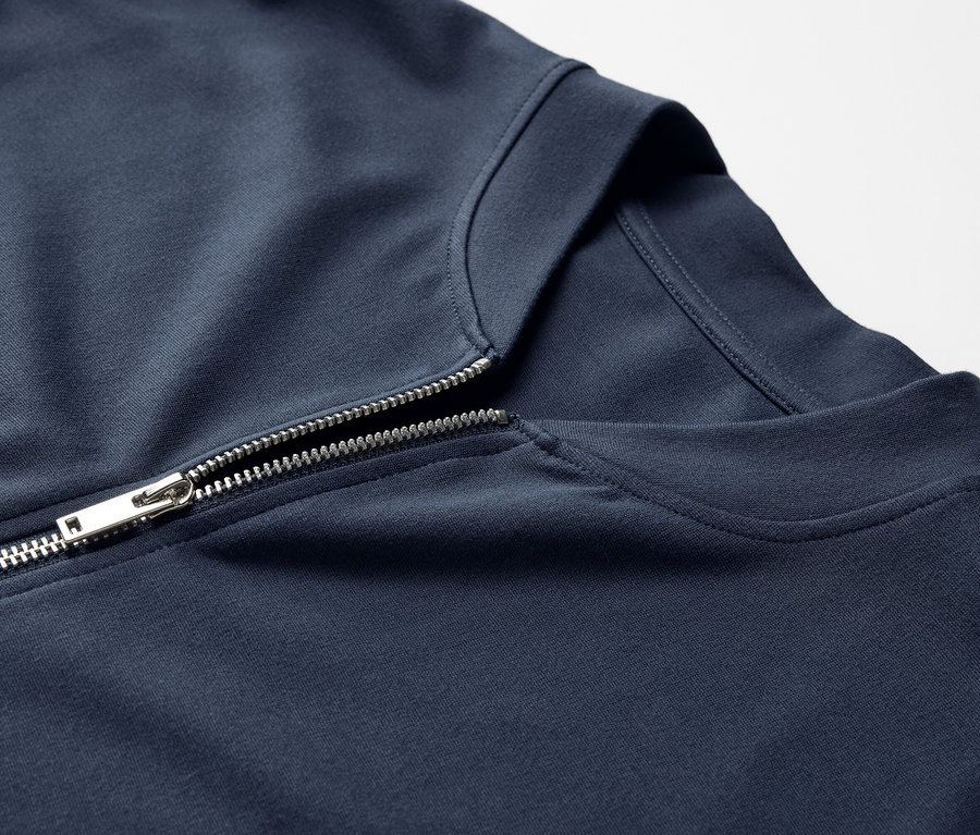 Detail modrej mikiny so strieborným zipsom.