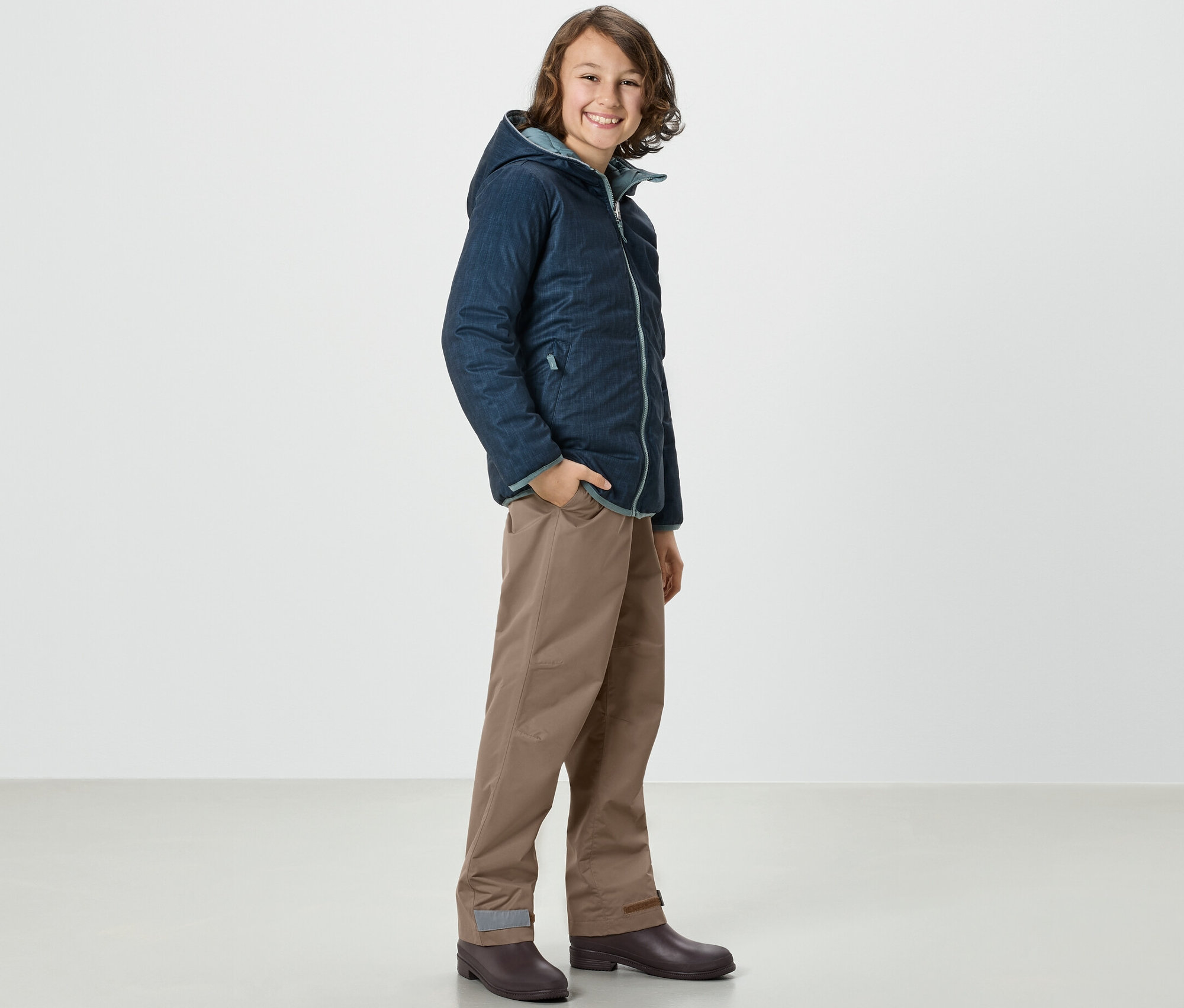 Chlapec v bunde a Kinder-Regenhose stojí zboku.