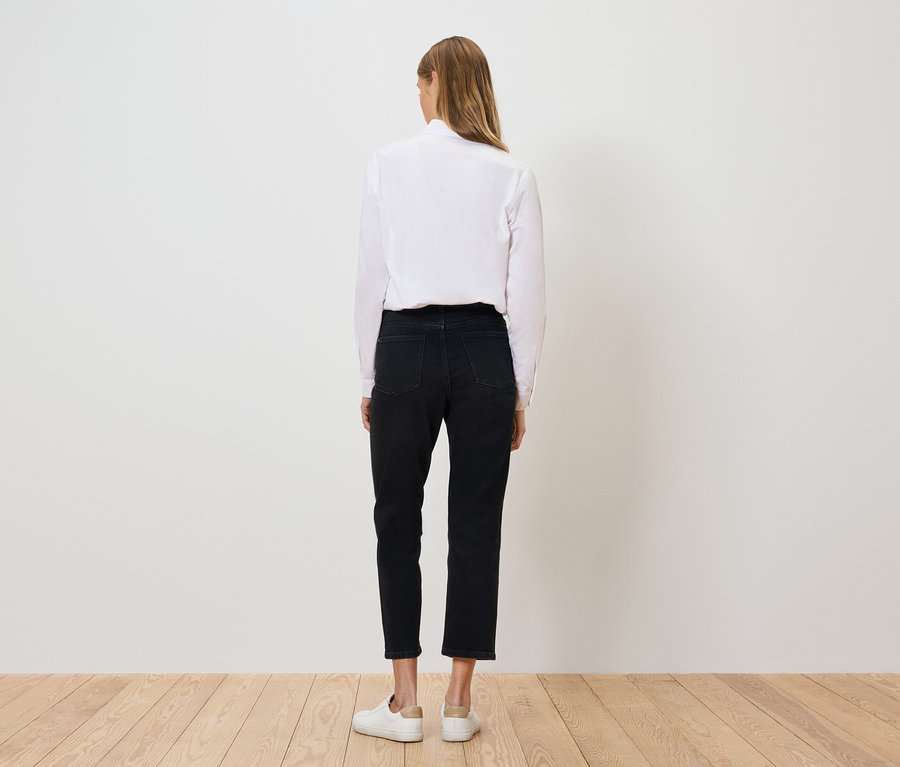 Zozadu je vidieť žena v bielej košeli, čiernych nohaviciach a bielych topánkach.