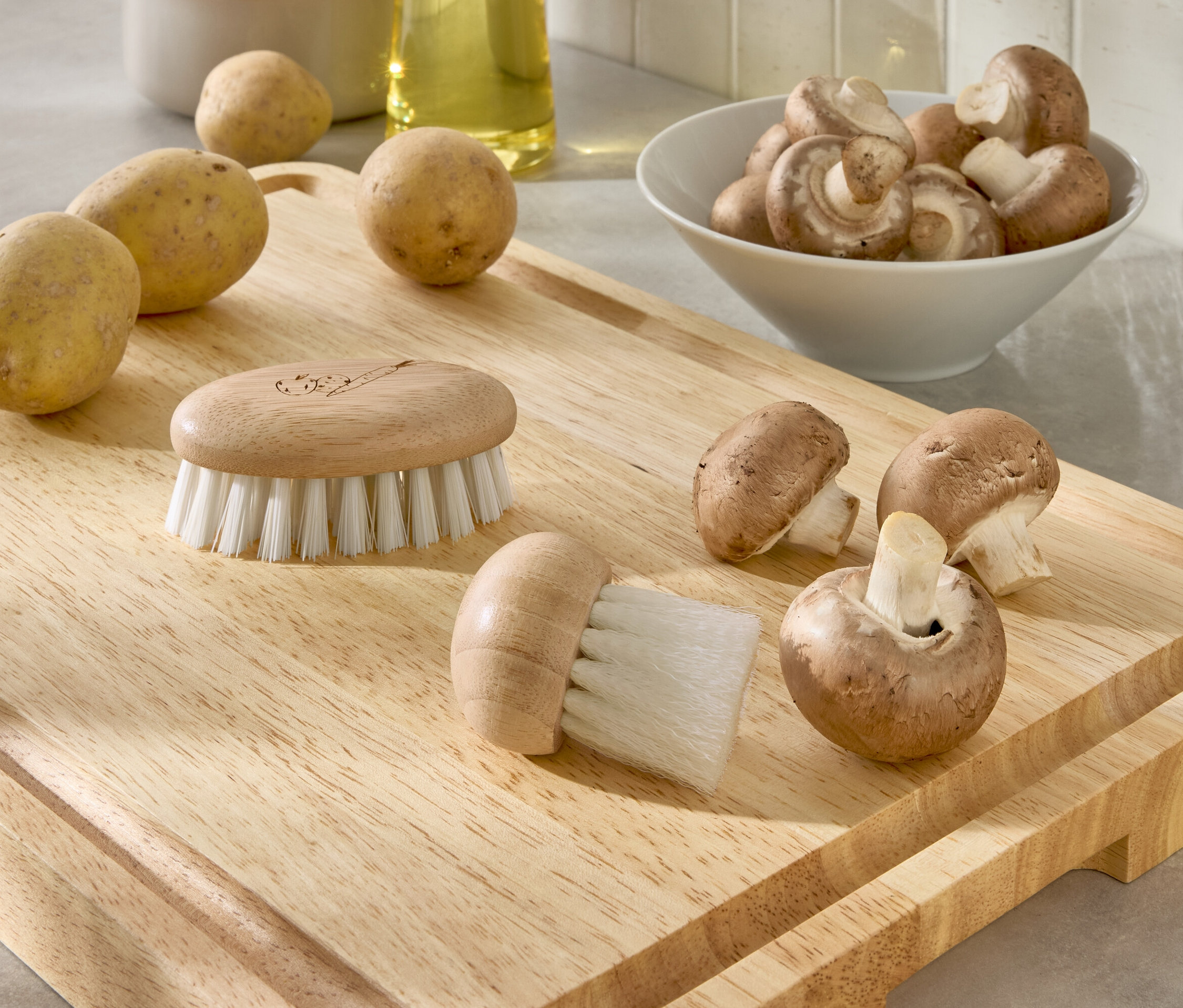 Na drevenej doske ležia zemiaky, huby a dve kefy.