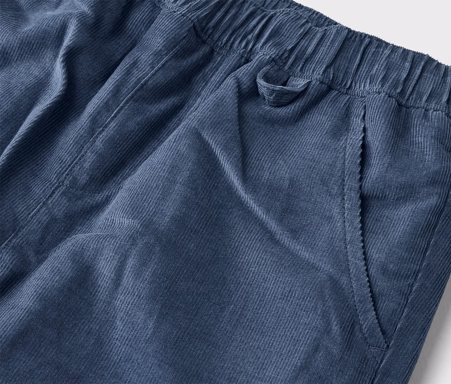 Detail modrých menčestrových nohavíc s elastickým pásom a bočným vreckom.