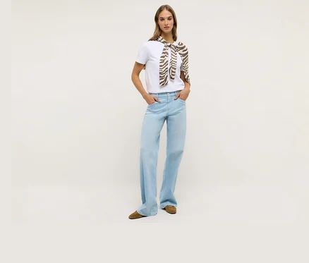 Žena v bielom tričku a džínsoch Angels Denim »Liz Modern« Wide Leg. Okolo ramien má uviazanú šatku so vzorom zebry.