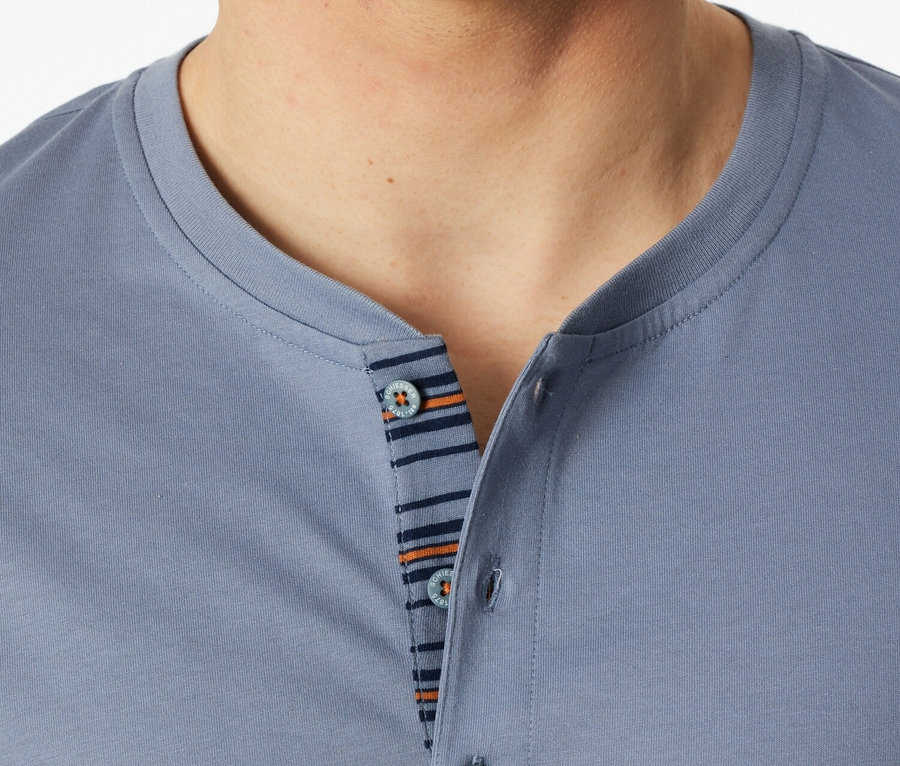 Detail muža v modrom polo tričku s gombíkmi a pruhovaným detailom.