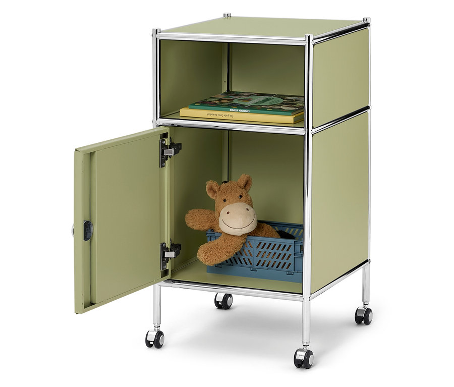 Otvorená, svetlozelená skrinka na kolieskach s knihou v hornej priehradke a plyšovou hračkou v modrej krabici v spodnej priehradke.
