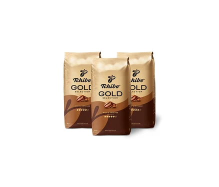 Tri balenia kávy Tchibo Gold Selection stoja na bielom pozadí.
