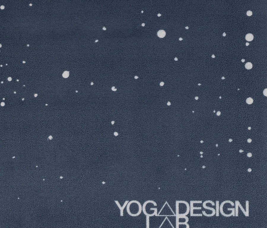 Detailný záber na tmavomodrú podložku na jogu s bielymi bodkami a logom Yoga Design Lab.