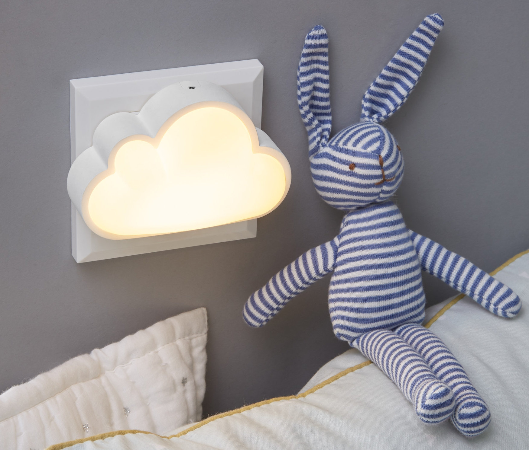 Na stene je namontované nočné svetlo s LED v tvare obláčika. Na vankúši sedí plyšový zajačik.