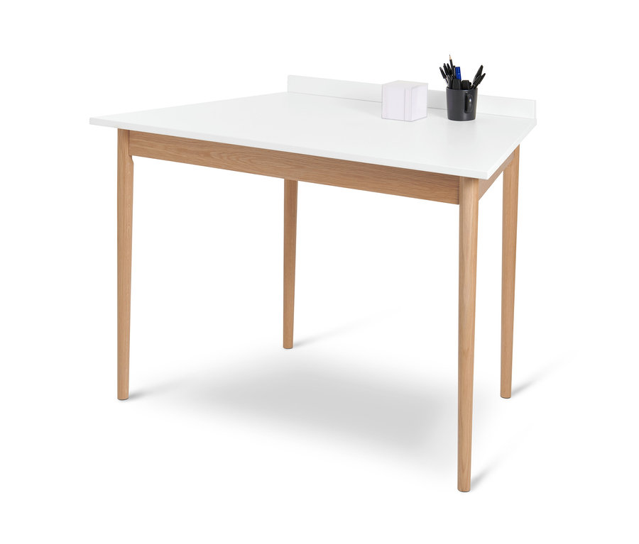 Biely lichobežníkový stôl so štyrmi drevenými nohami a čiernym hrnčekom s písacími potrebami.