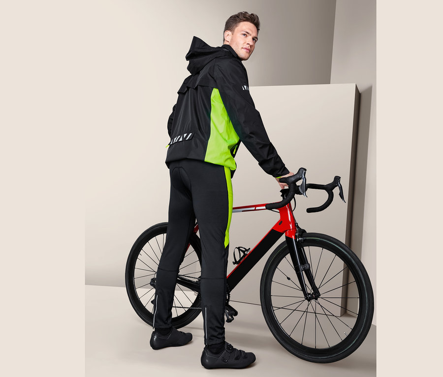 Muž pózuje vedľa bicykla v cyklistických nohaviciach.