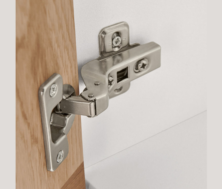 Detail strieborného pántu na vysokej skrinke s 2 dvierkami.