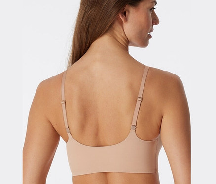 Pohľad zozadu na ženu s hnedými vlasmi, ktorá má na sebe telovú neviditeľnú podprsenku s vložkami SCHIESSER.