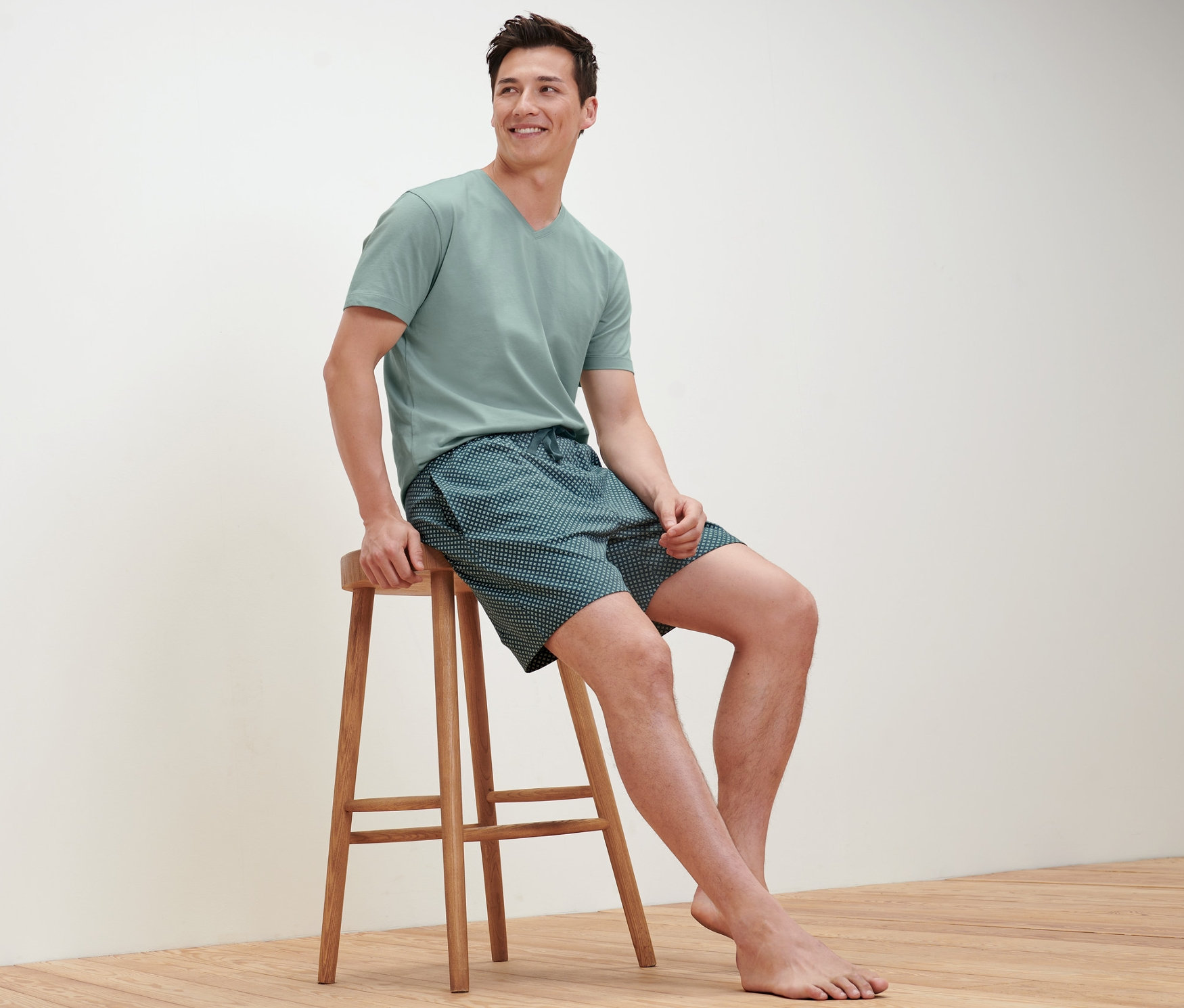 Muž sedí na stoličke a má na sebe krátke pyžamo.