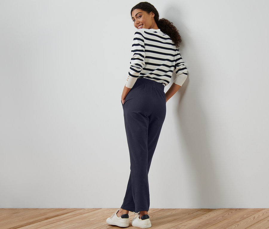 Žena stojí a pózuje v námorníckych modrých pohodlných nohaviciach.