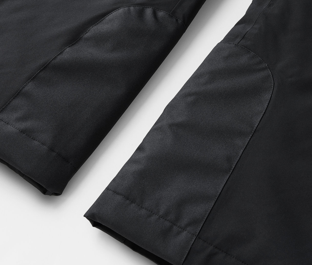 Detail čiernych nohavíc s kontrastnými panelmi.
