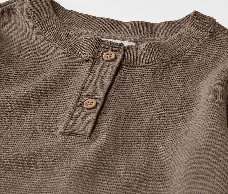 Detail hnedého detského pleteného svetra henley s gombíkmi.