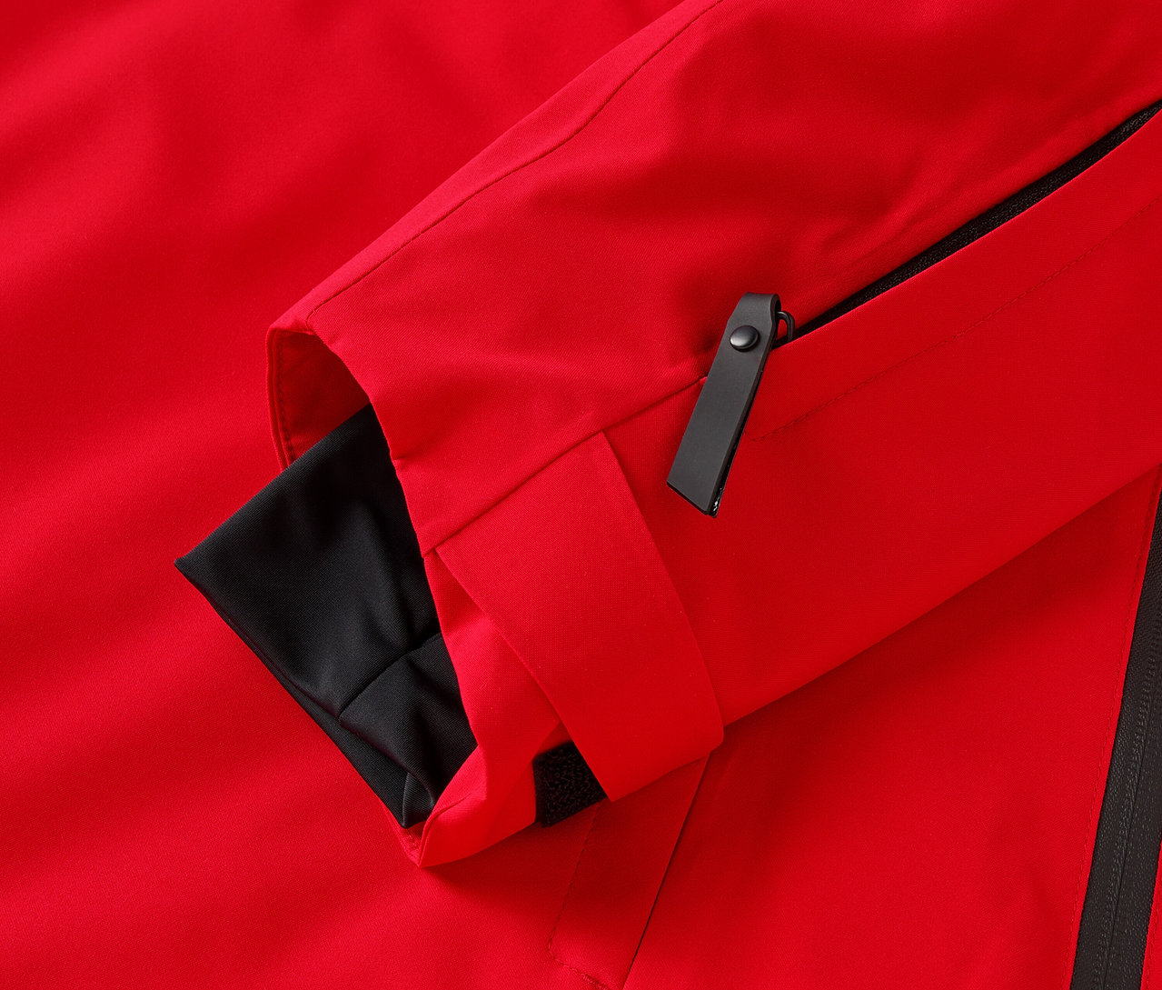 Detail červenej bundy s čiernymi detailmi.