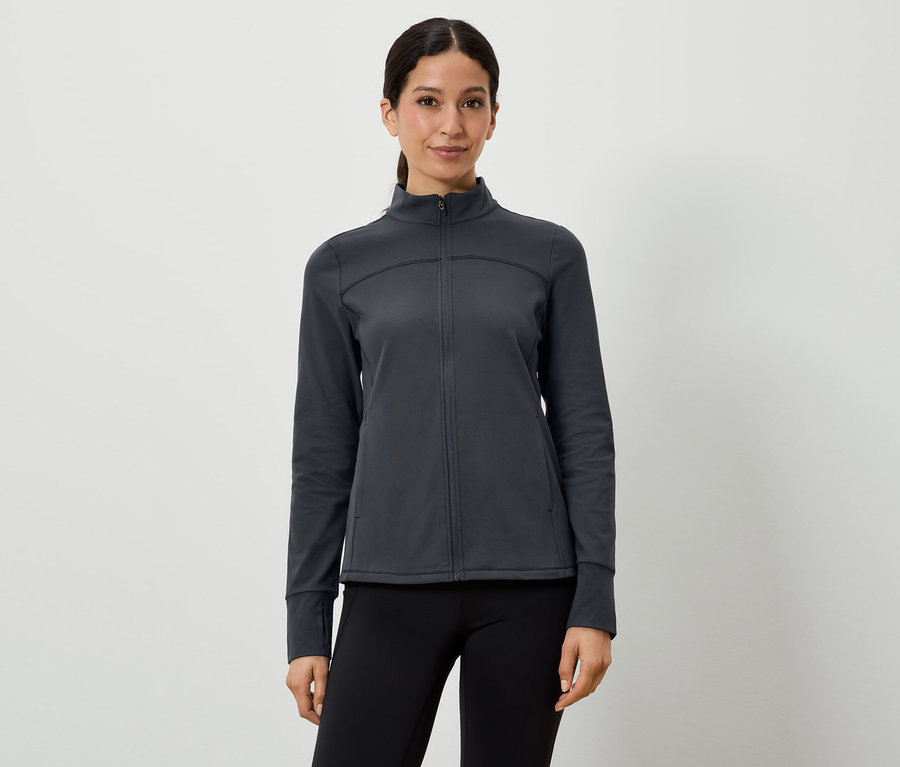 Žena má na sebe tmavosivú športovú bundu a čierne legíny.