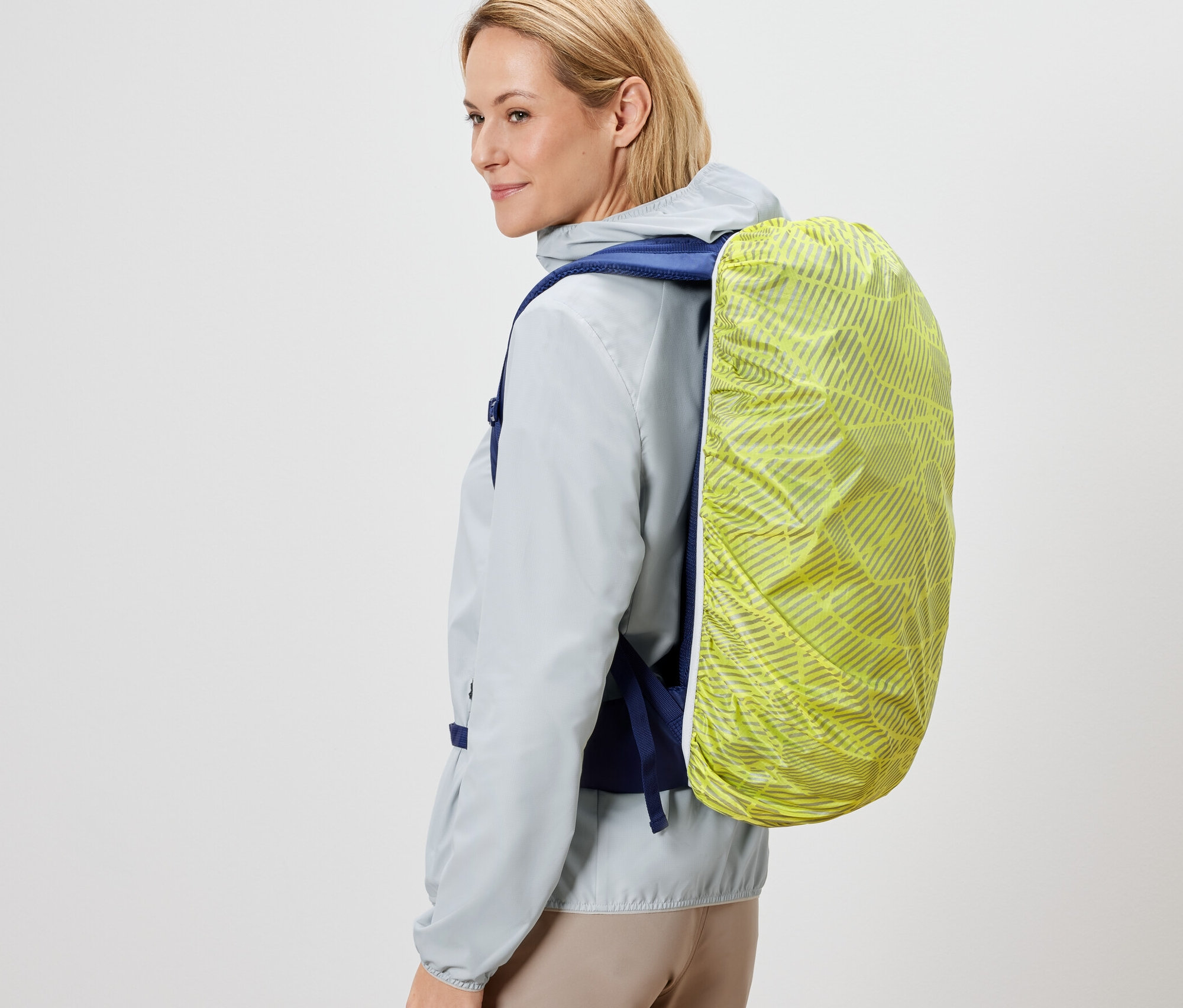 Žena má na chrbte ruksak s nepremokavým ochranným návlekom.