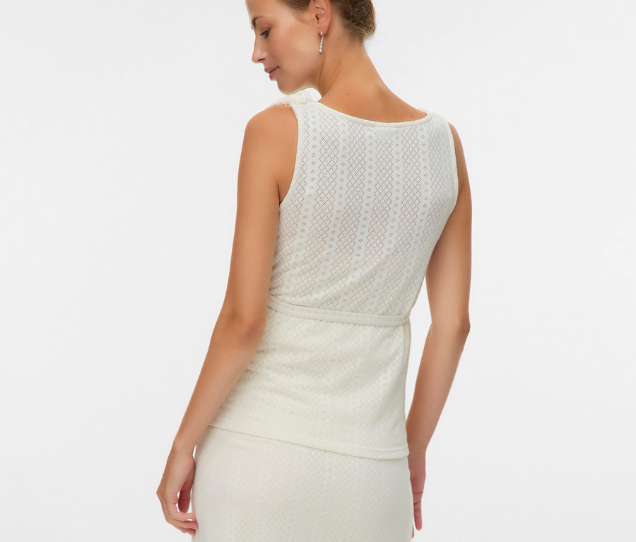 Žena zozadu v tope bez rukávov a sukni so vzorom.