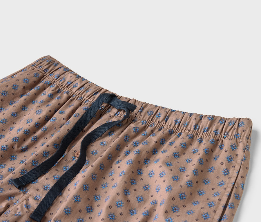 Detail béžových nohavíc s modrou kvetinovou potlačou a tmavomodrou šnúrkou.