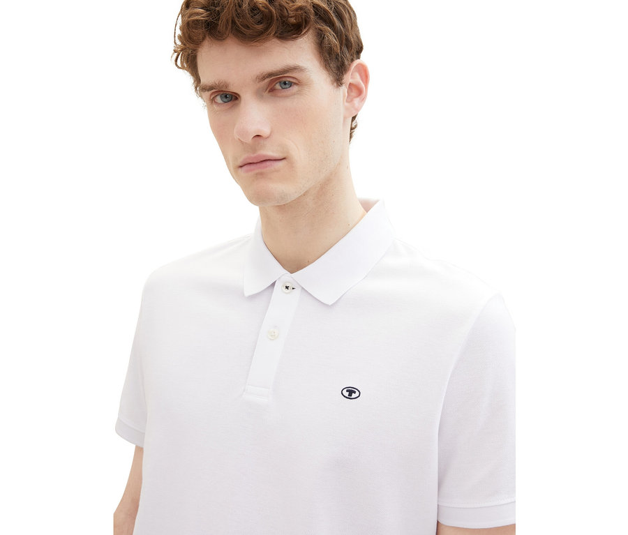 Muž má na sebe biele piké polokošeľu Tom Tailor.