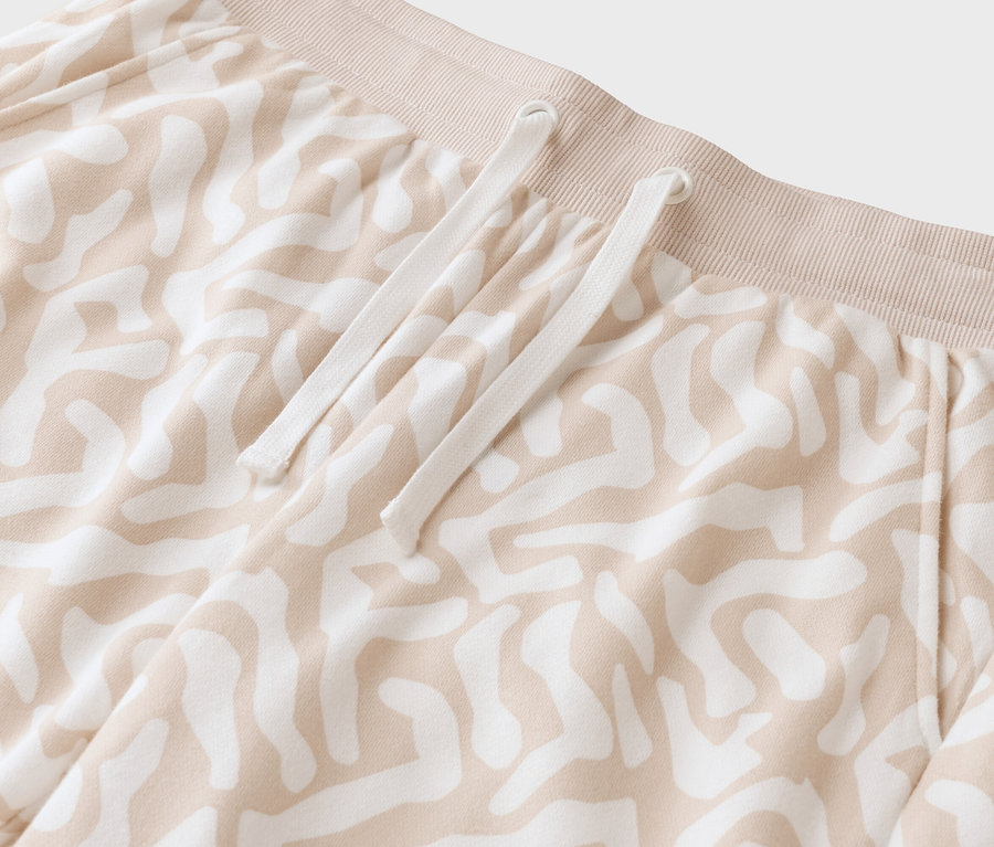 Detail béžových nohavíc so vzorom s bielou šnúrkou.