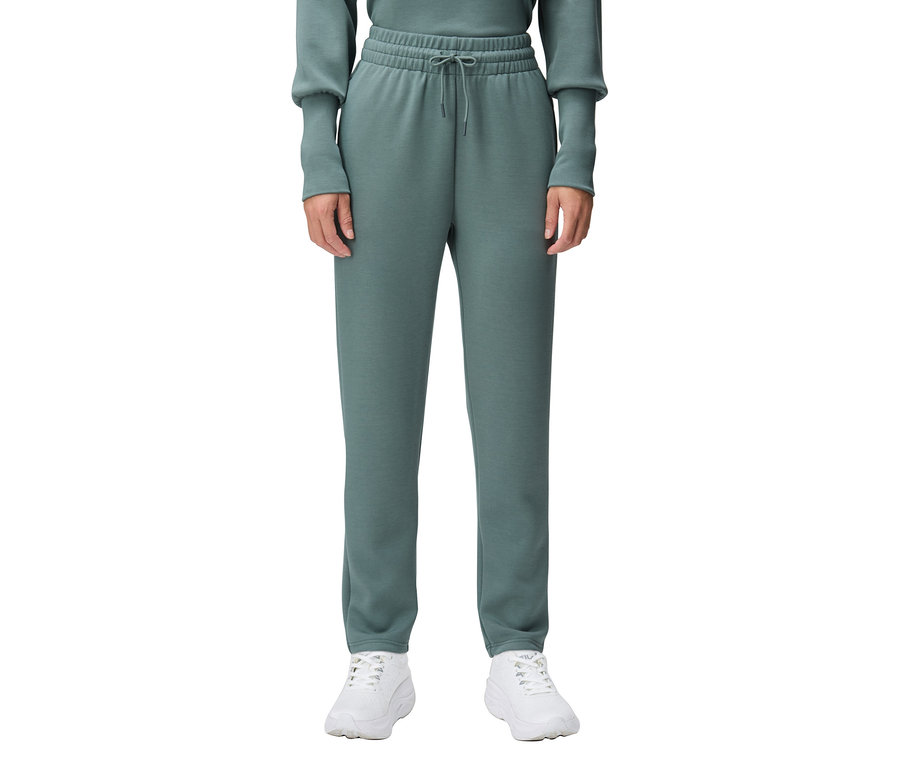 Osoba má na sebe zelené tepláky a biele tenisky.