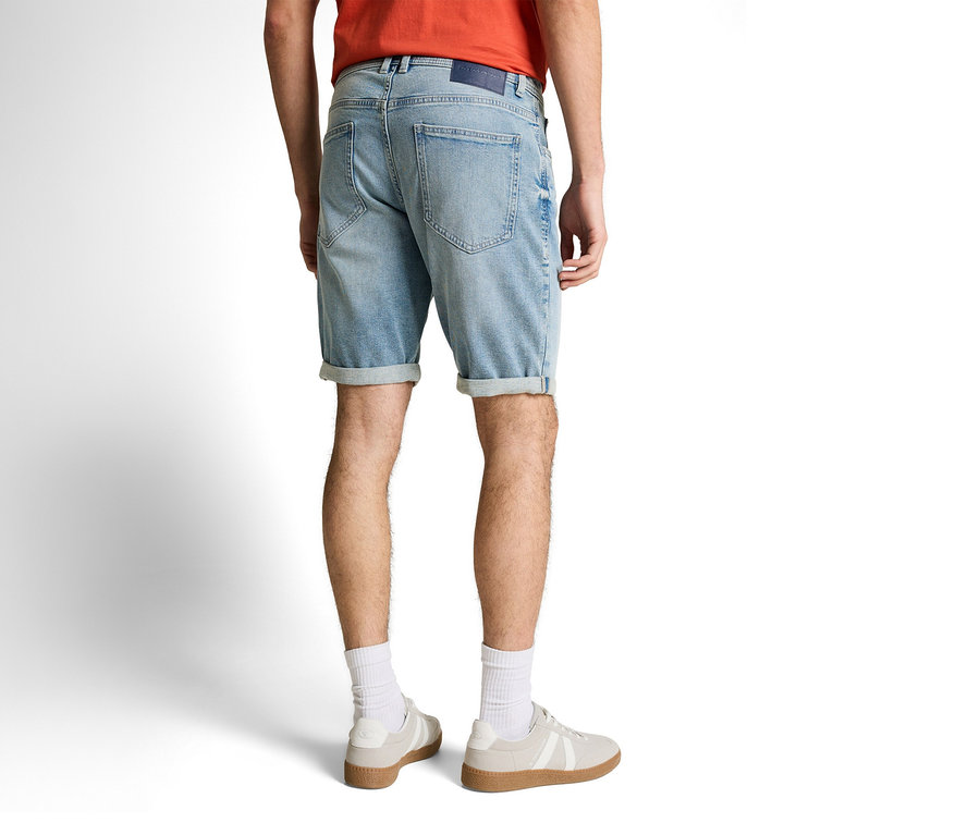 Muž zozadu v džínsových šortkách Tom Tailor TTJOSH REGULAR SLIM, light stone blue denim, bielych ponožkách a teniskách.