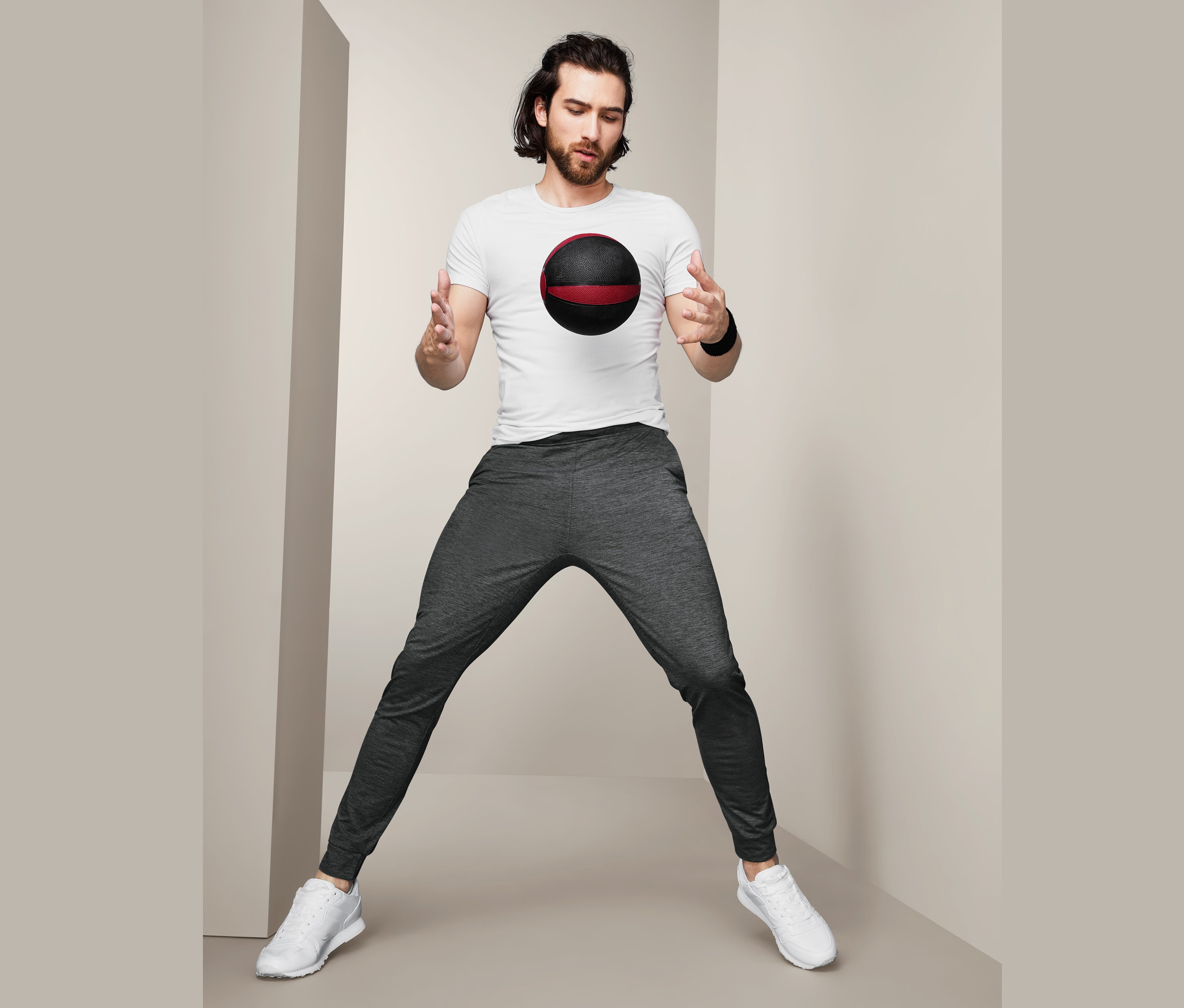 Muž v sivých funkčných nohaviciach pózuje s medicinbalom.