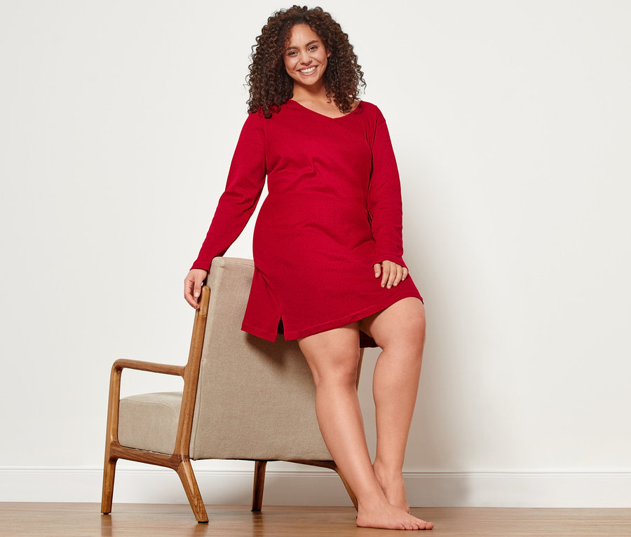 Žena sedí na stoličke v ažúrovej nočnej košeli.