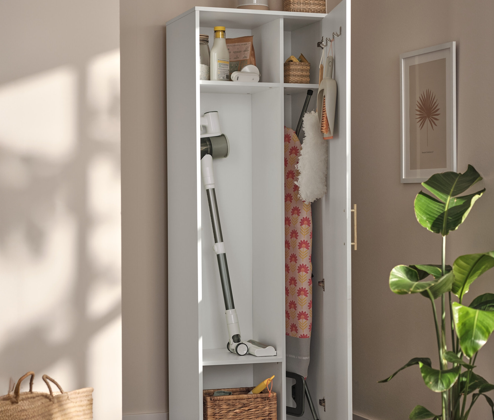 Otvorená biela univerzálna skrinka s vysávačom, žehliacou doskou a košmi vo vnútri.