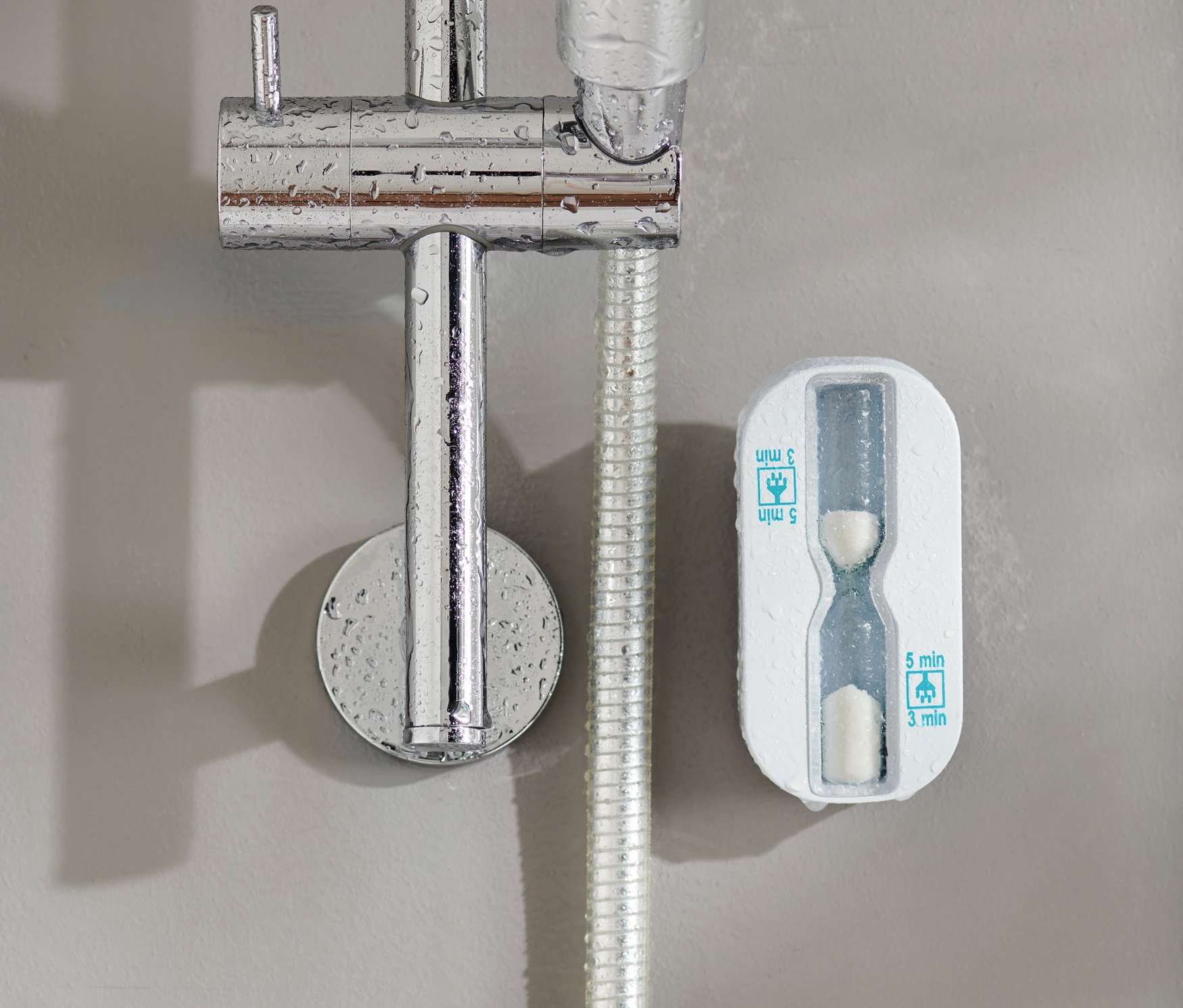 Sprchové hodiny pripevnené na stene vedľa sprchovej hlavice.