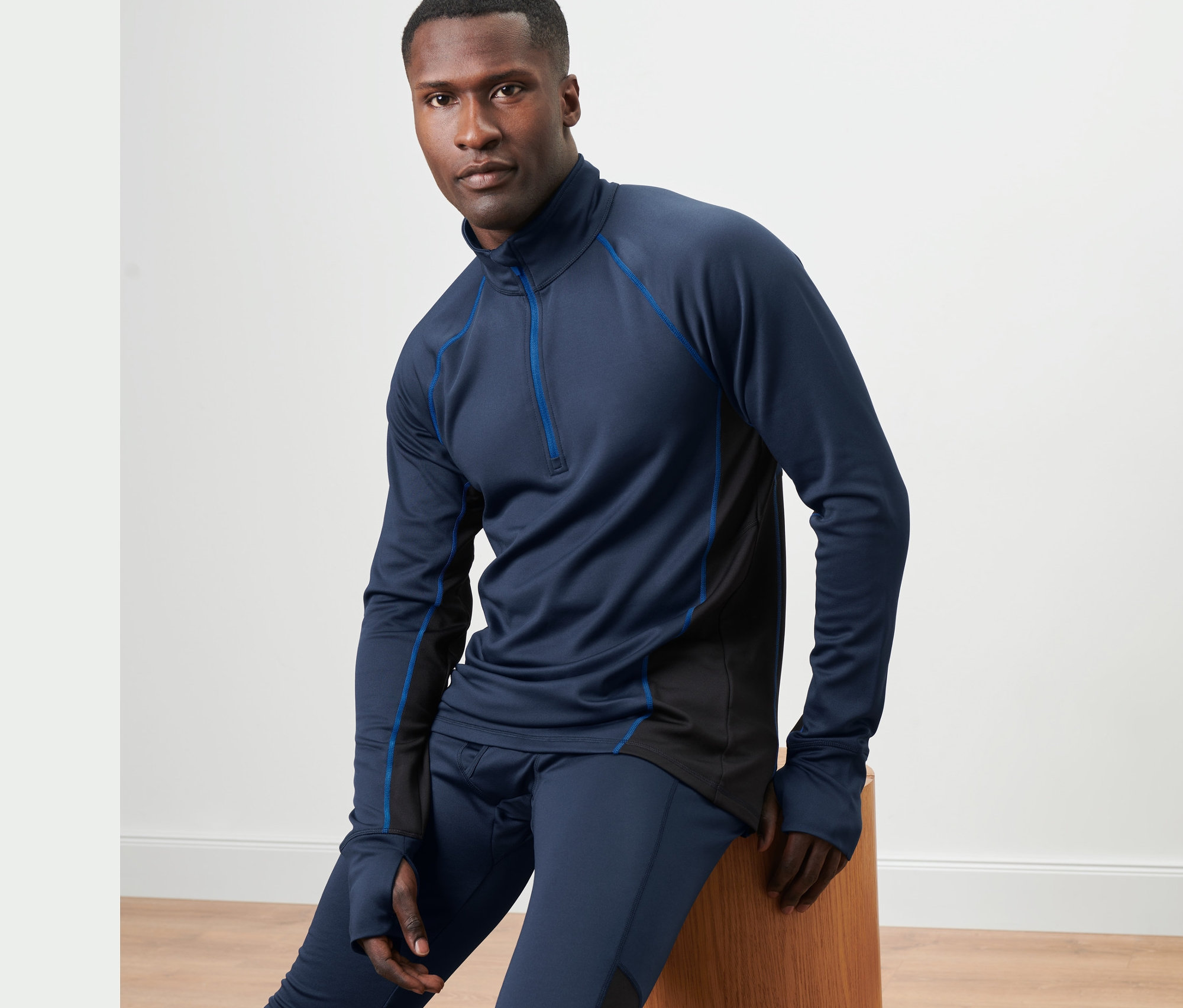 Muž sedí na drevenej stoličke a má na sebe modré funkčné termotričko.