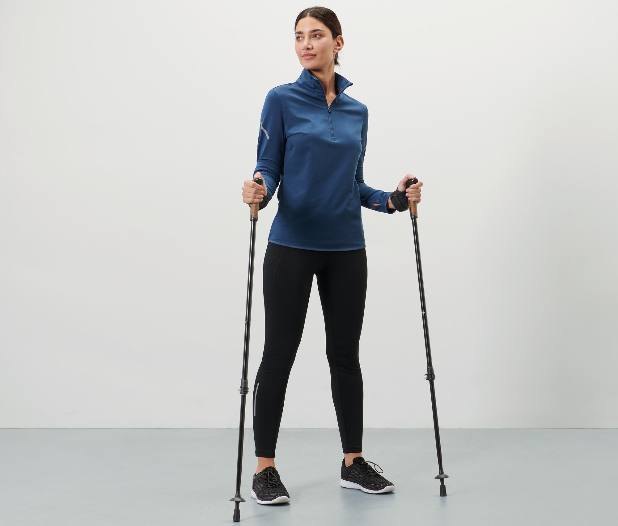 Žena drží teleskopické trekingové palice.
