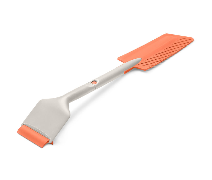 Zastrčená škrabka na ľad do auta s oranžovou škrabkou a hrebeňom na ľad.