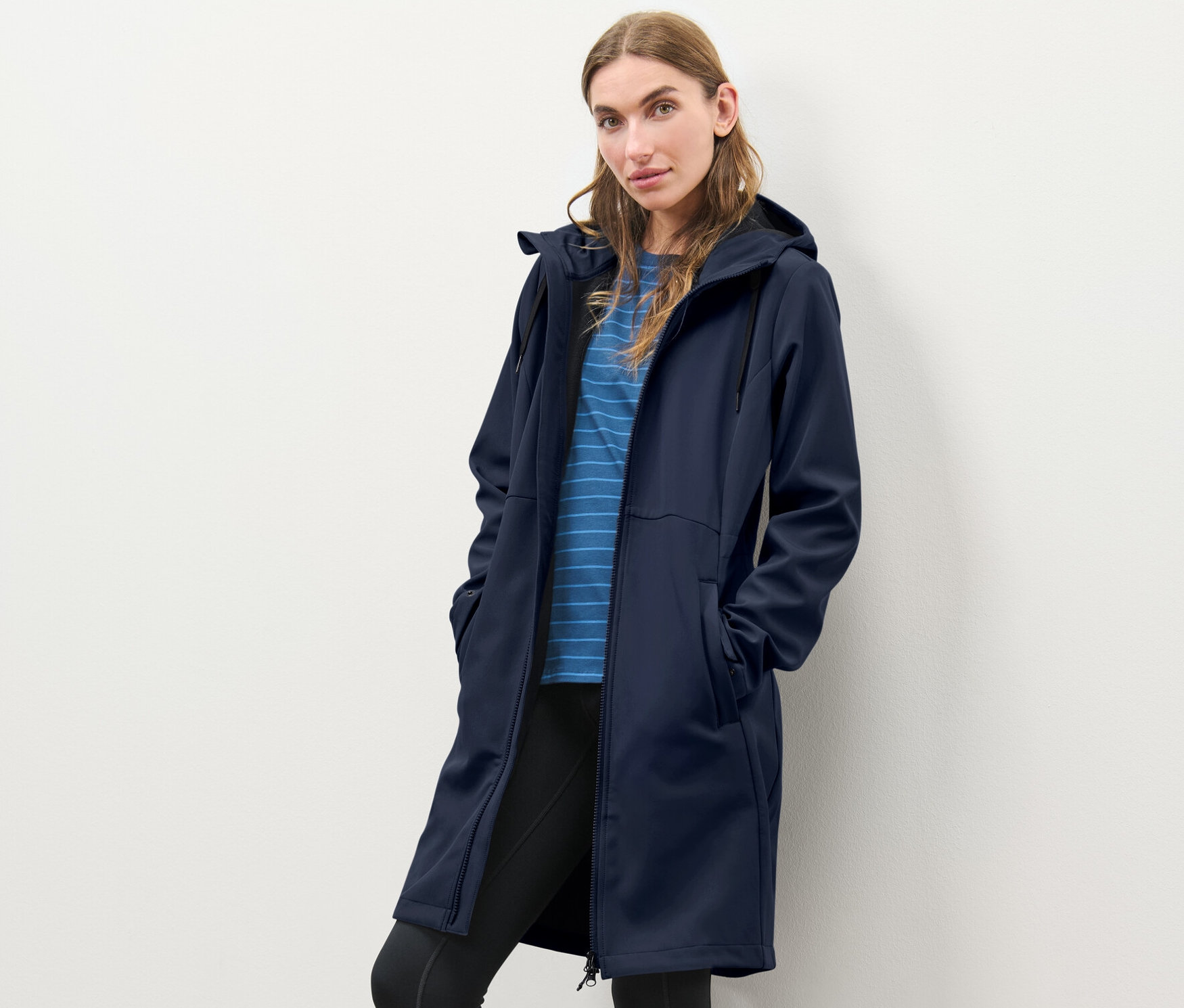 Žena pózuje v modrom softshellovom kabáte.