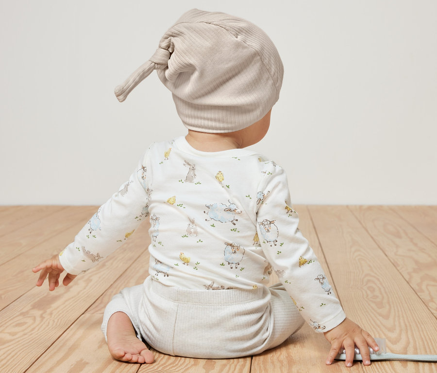 Dieťa sedí chrbtom k fotoaparátu a má na sebe dojčenské džersejové čiapky, 2 ks.