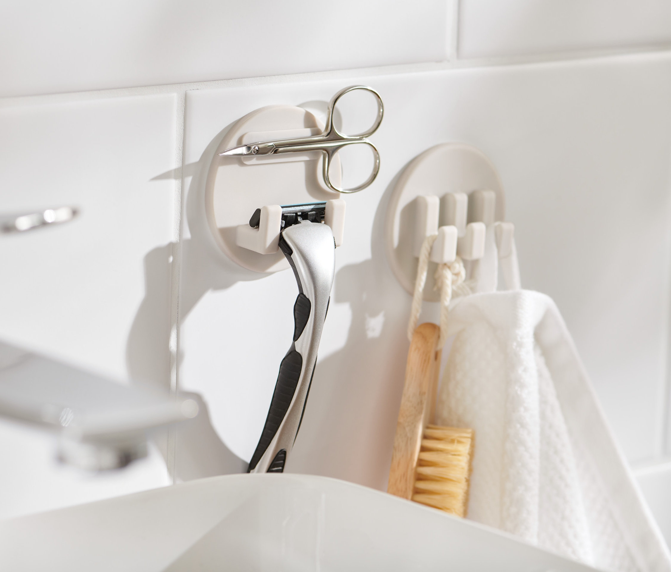 Dve samolepiace súpravy držiakov na bielych kachličkách, v jednom je umiestnená žiletka a nožnice.